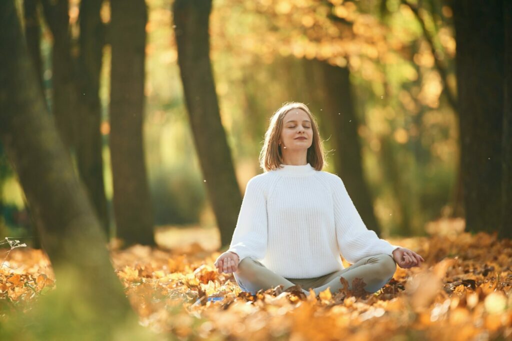 Front view. Young beautiful woman is doing yoga in the autumn park